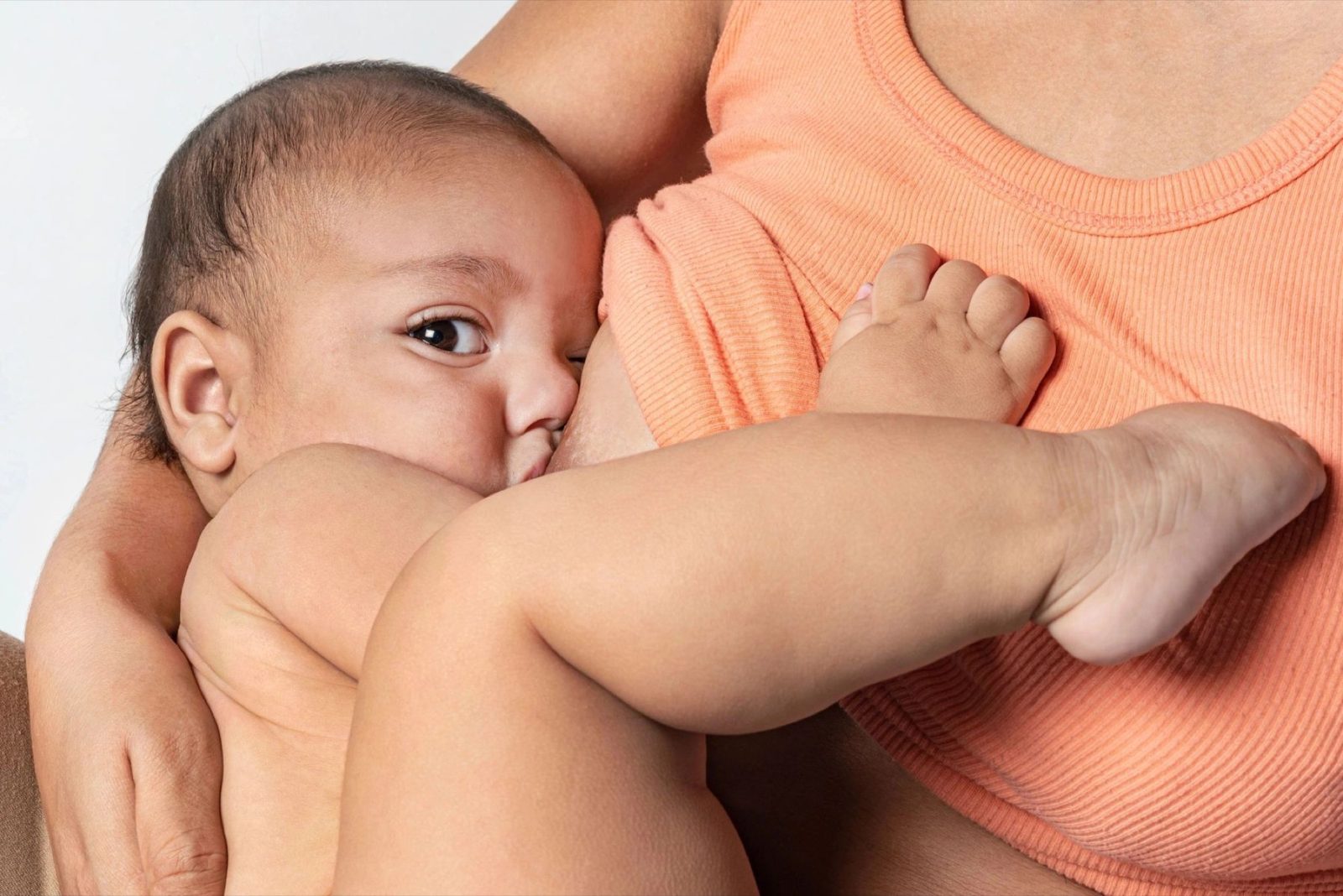 A baby feeding, one hand resting on her parent.